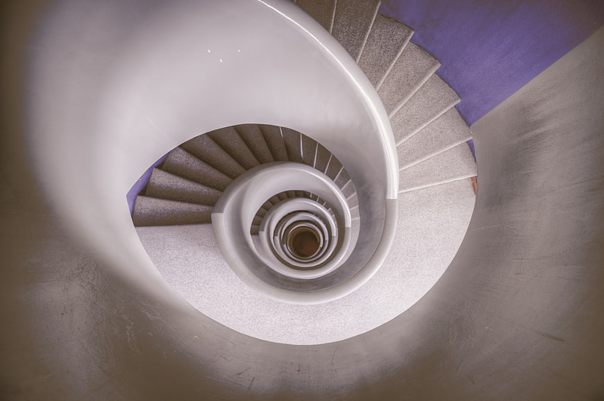 Top-down view of modern white spiral staircase with purple wall