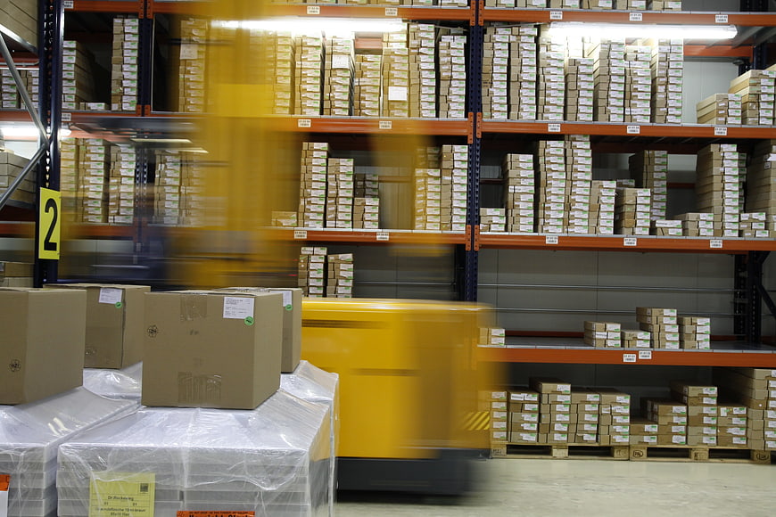 Motion blur of yellow forklift in busy warehouse aisle