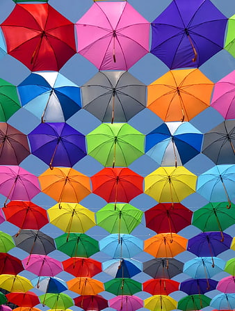 Colorful umbrellas hanging against blue sky pattern