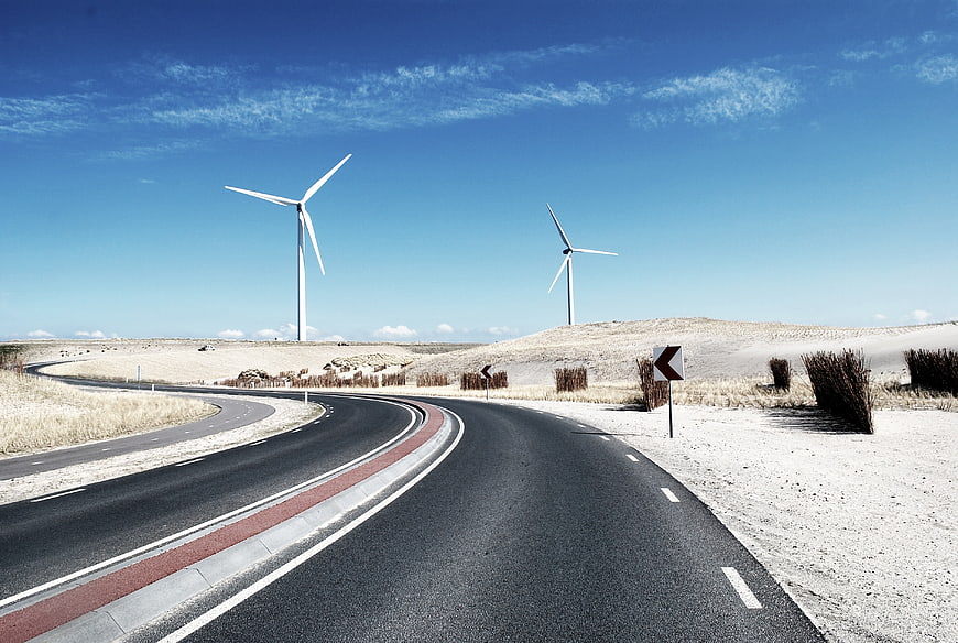 Winding asphalt road with wind turbines in arid landscape
