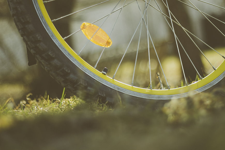 Close-up of yellow bicycle wheel on grass