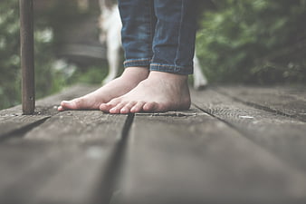 Bare feet on wooden deck with blurred dog background