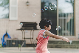 Happy child playing with bubbles in backyard