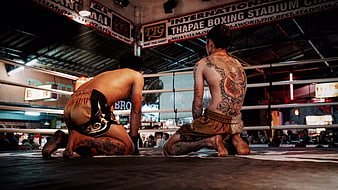 Muay Thai fighters kneeling in boxing ring