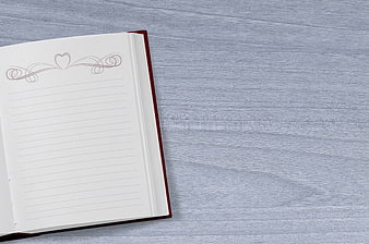 Open lined notebook with heart design on gray wood background