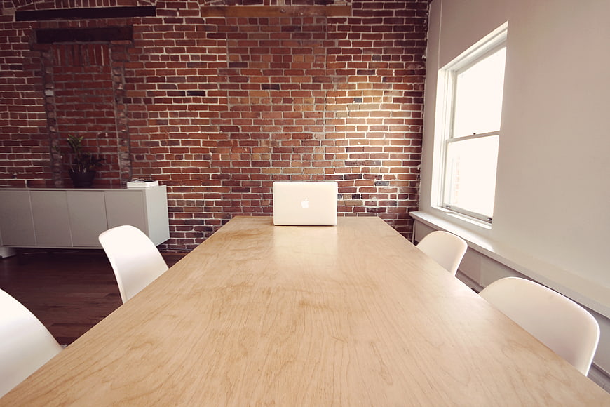 Modern office workspace with laptop on wooden table against brick wall