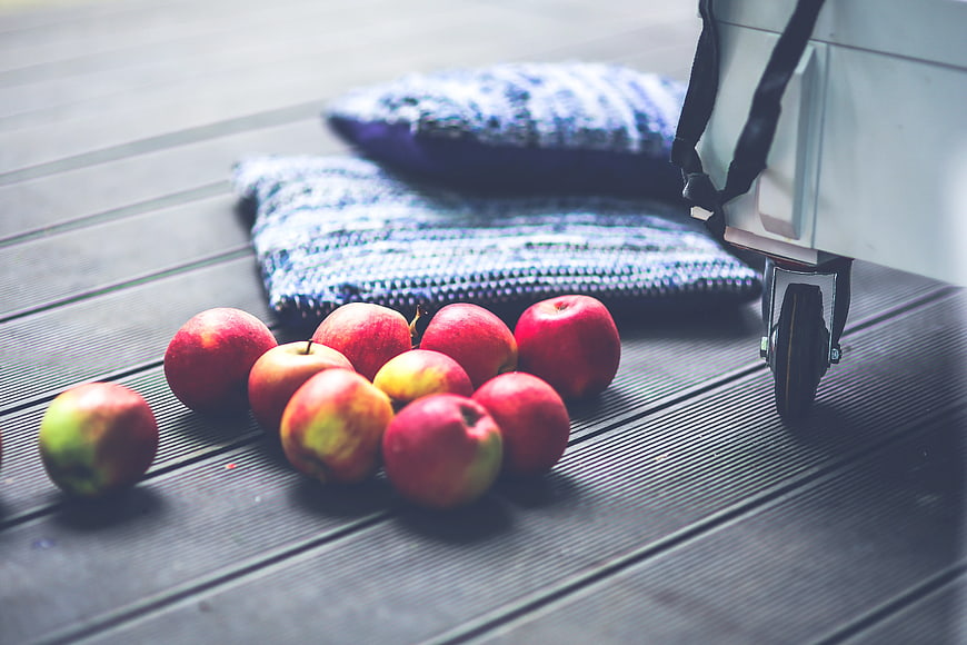 Red apples on wooden deck with blue pillows