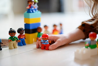 Child playing with colorful toy figures and blocks