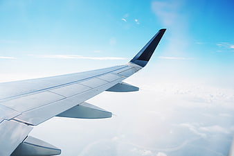Airplane Wing View Over Clouds and Blue Sky