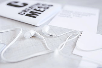 White Acer earphones on a desk with notebook
