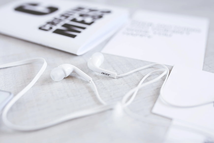 White Acer earphones on a desk with notebook