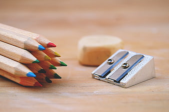 Colorful Pencils, Sharpener, and Eraser on Wooden Desk