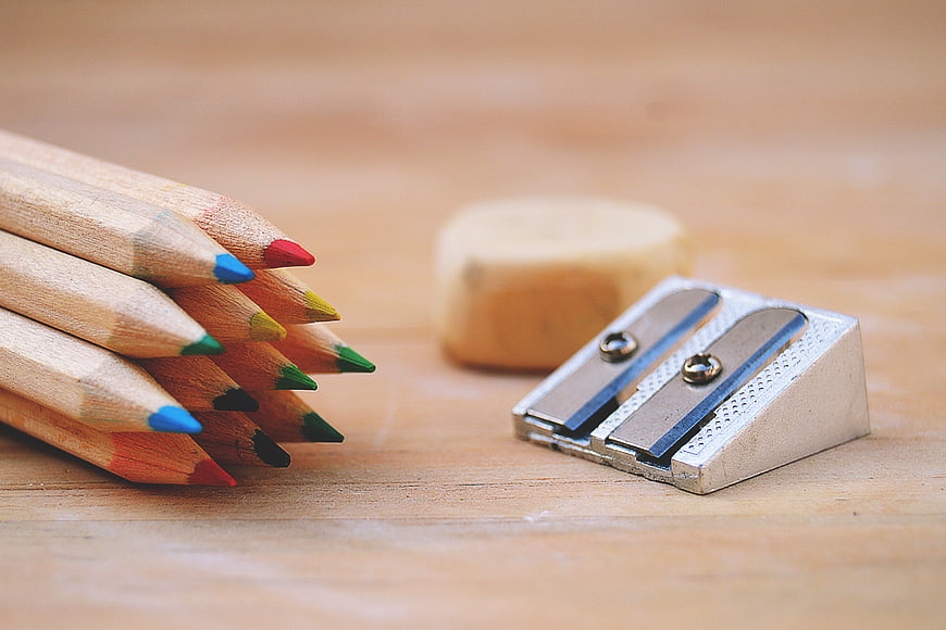 Colorful Pencils, Sharpener, and Eraser on Wooden Desk