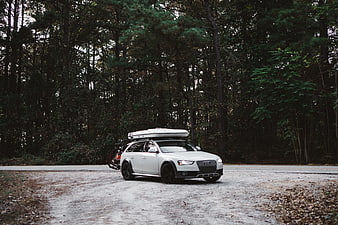 White Audi Allroad with Roof Box and Bikes in Forest