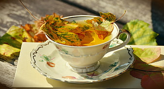 Autumn Tea Cup with Fallen Leaves on Wooden Table