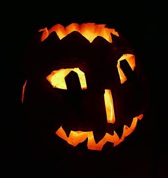 Glowing Jack-O-Lantern with Carved Face in Dark Setting