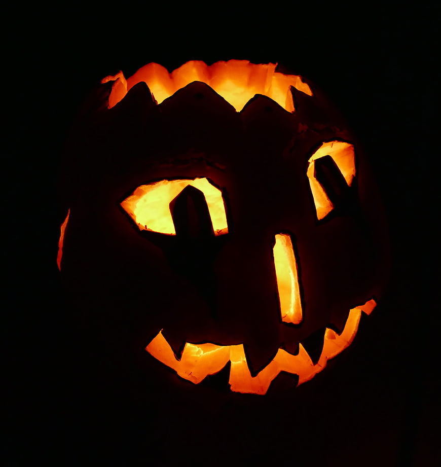 Glowing Jack-O-Lantern with Carved Face in Dark Setting