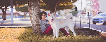 Woman Sitting with White Samoyed Dog in Park