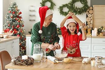 Grandmother and granddaughter baking Christmas cookies in festive kitchen