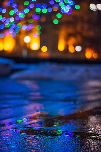 Colorful Bokeh Lights Reflecting on Wet Pavement at Night