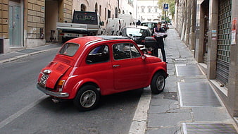 Red vintage car parked on narrow European street