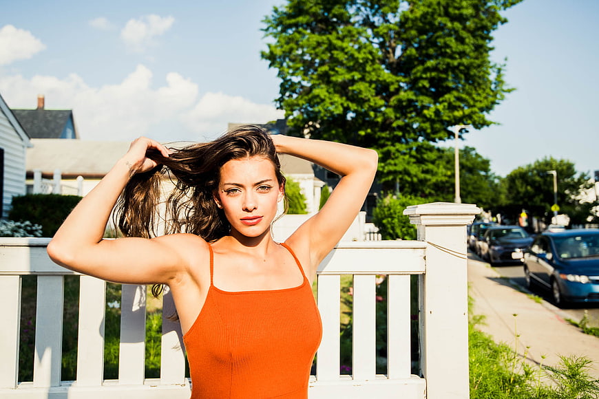 Confident woman in orange top posing outdoors