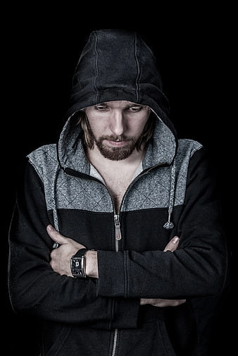 Pensive man in black hoodie looking down with arms crossed