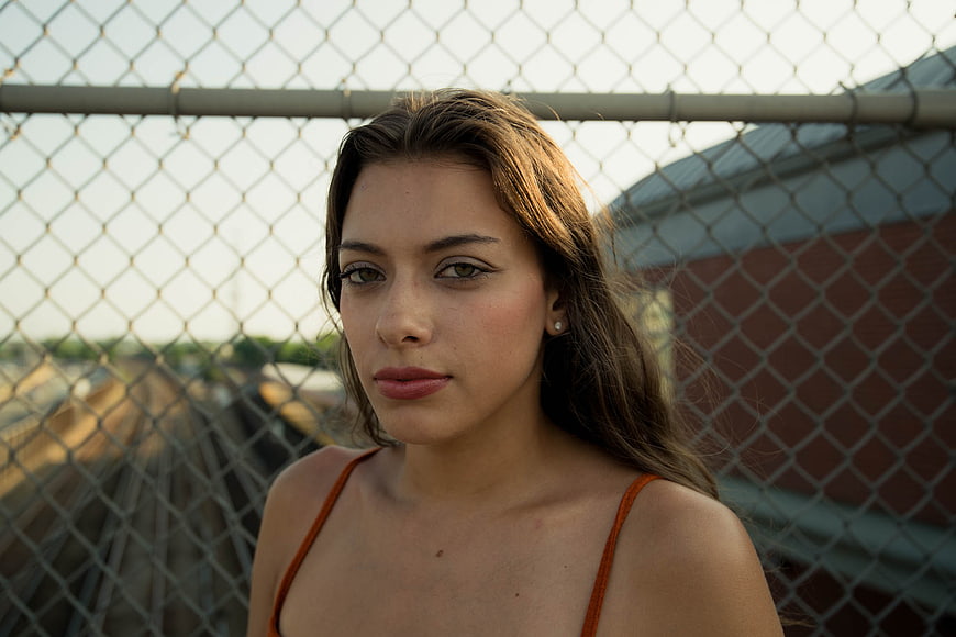 Portrait of young woman with chain link fence background
