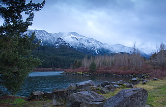 Snow-capped mountains and lake landscape with evergreen trees
