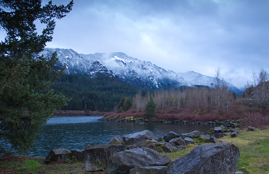 Snow-capped mountains and lake landscape with evergreen trees