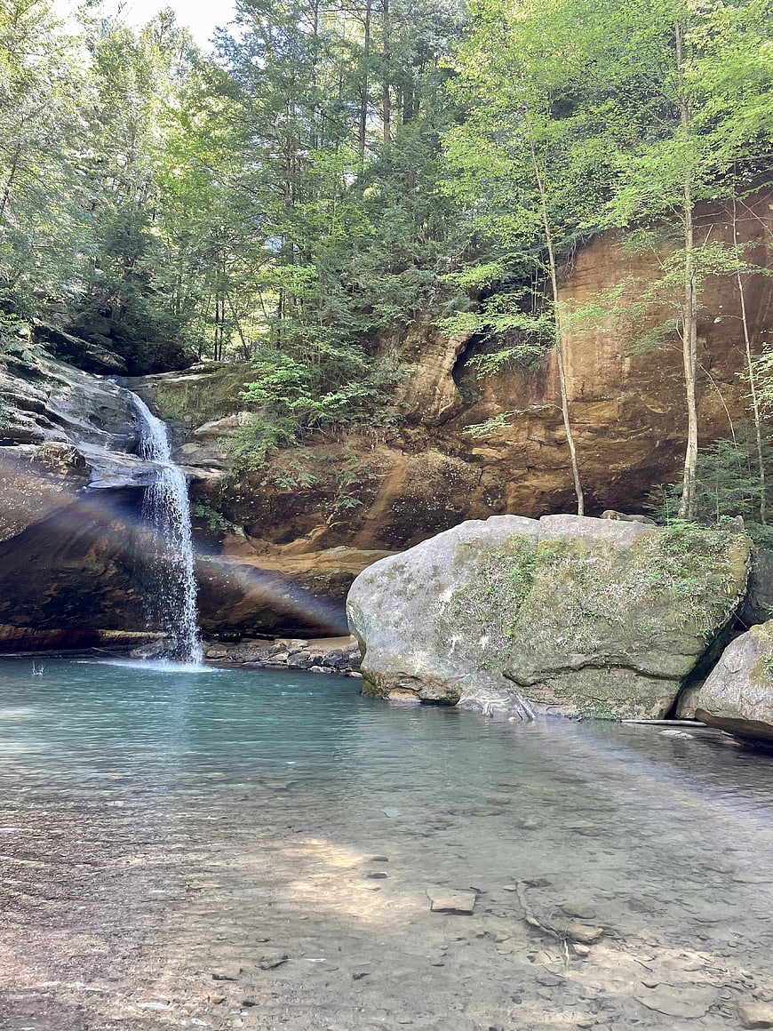 Serene waterfall cascading into a clear pool in a lush forest