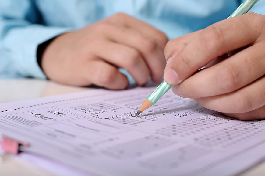 Close-up of hands filling out a standardized test form with a pencil