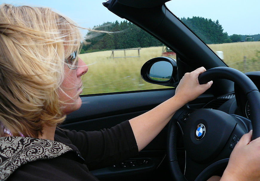 Woman driving convertible car through countryside landscape