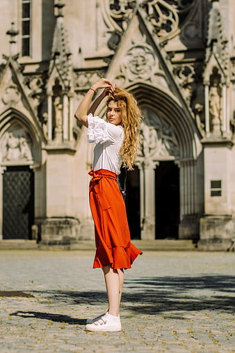 Woman in Red Skirt Standing Before Gothic Cathedral Facade