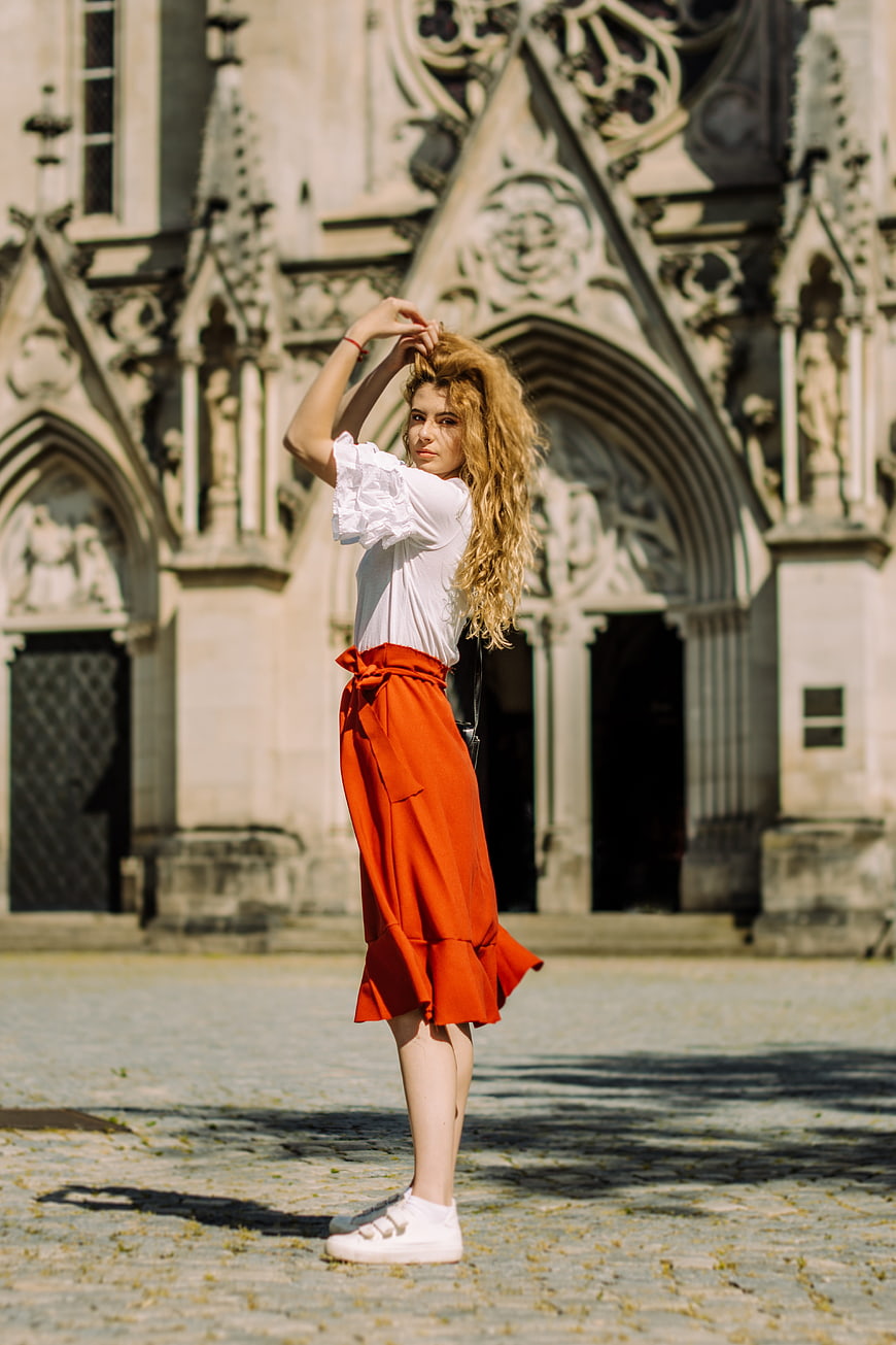 Woman in Red Skirt Standing Before Gothic Cathedral Facade