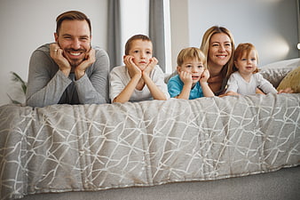 Happy family of five lying on bed looking at camera