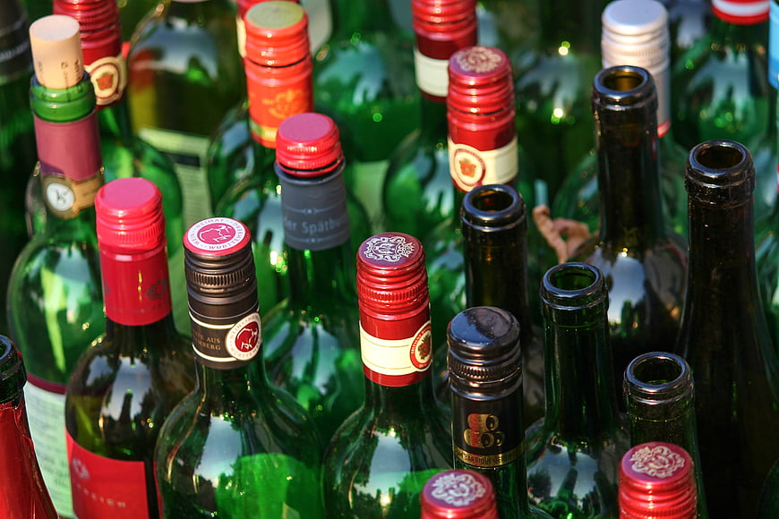 Close-up of assorted green glass wine bottles with colorful caps