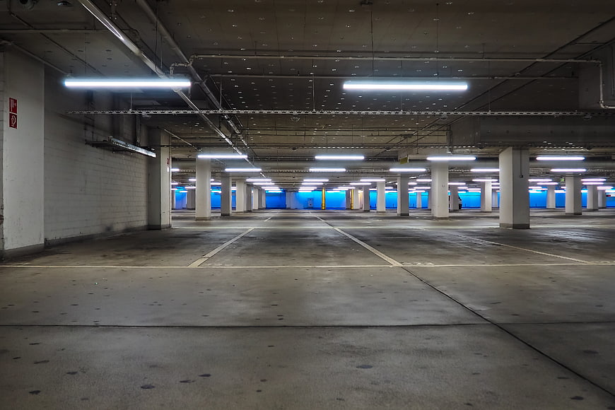 Empty Underground Parking Garage With Concrete Columns And Fluorescent Lighting