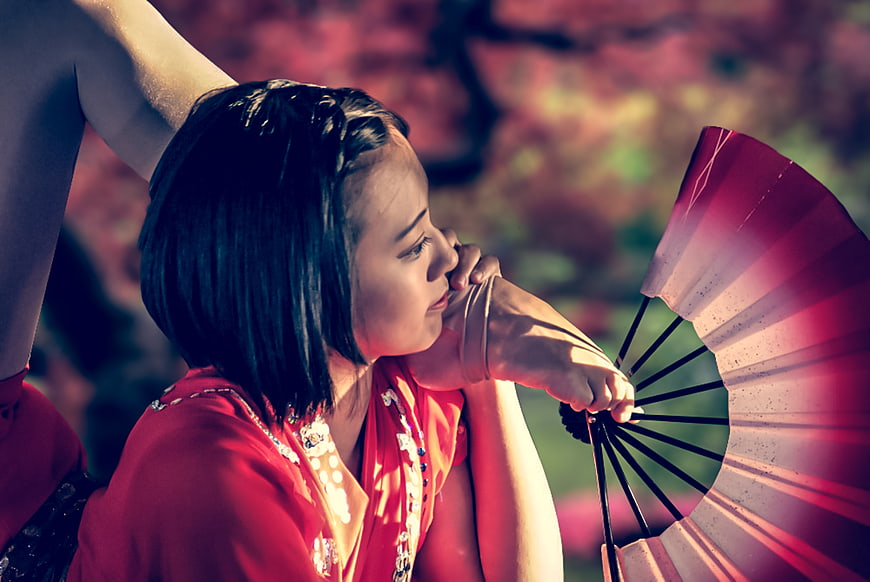 Female contortionist performing cultural dance with fan