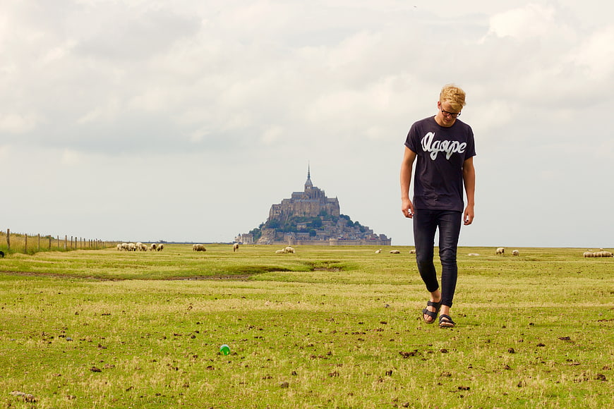 Man walking in field with Mont Saint-Michel in background