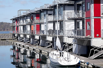 Modern floating houses with red accents and docked sailboat