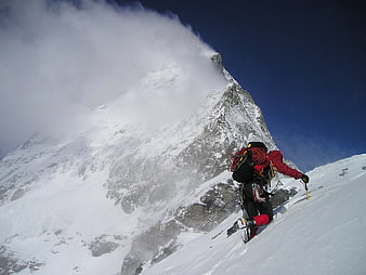 Alpine Climber Ascending Snowy Mountain Ridge in Storm