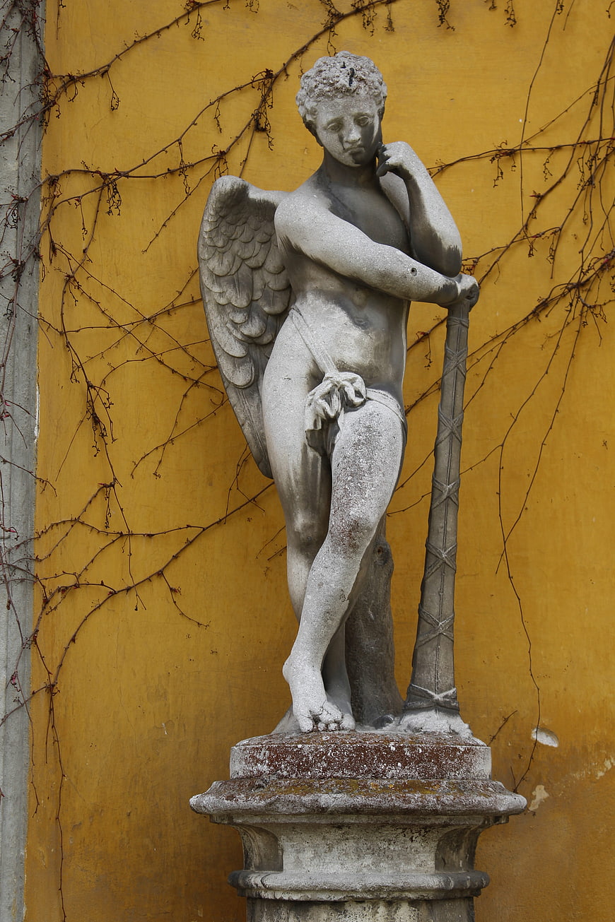 Stone Angel Statue Against Yellow Wall with Vines