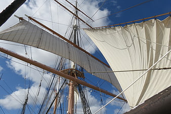 Close-up of tall ship sails and rigging against blue sky