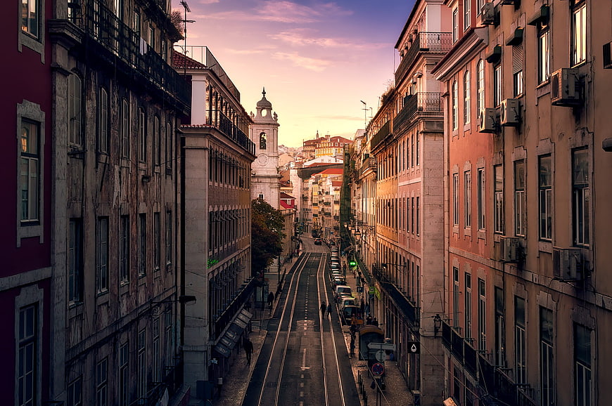 Lisbon street view with tram tracks and church at sunset