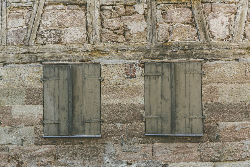 Weathered Wooden Shutters On Old Stone Building Facade