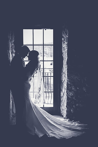 Silhouette of Bride and Groom Embracing by Window