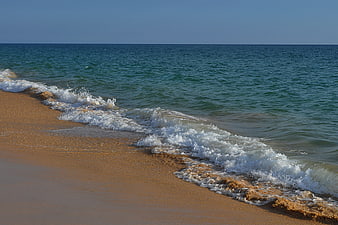 Gentle turquoise waves washing onto golden sandy beach