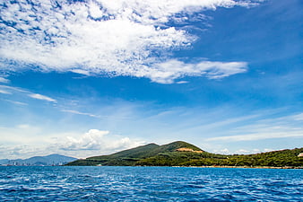Blue Ocean View with Green Hills and Cloudy Sky