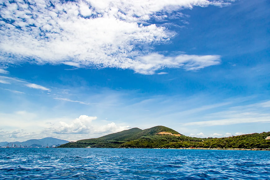 Blue Ocean View with Green Hills and Cloudy Sky